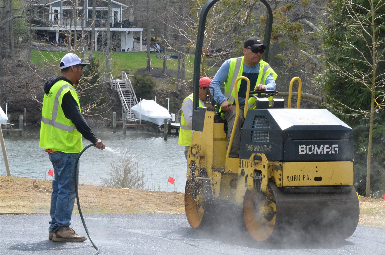 Roller compacting fresh asphalt on a waterfront driveway